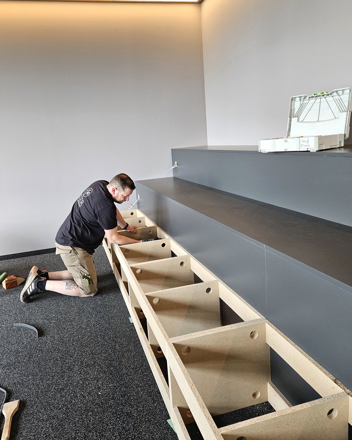 Tischler der Holzmanufaktur Geier montiert eine Einbauwand beim Kunden vor Ort – Montage Essen