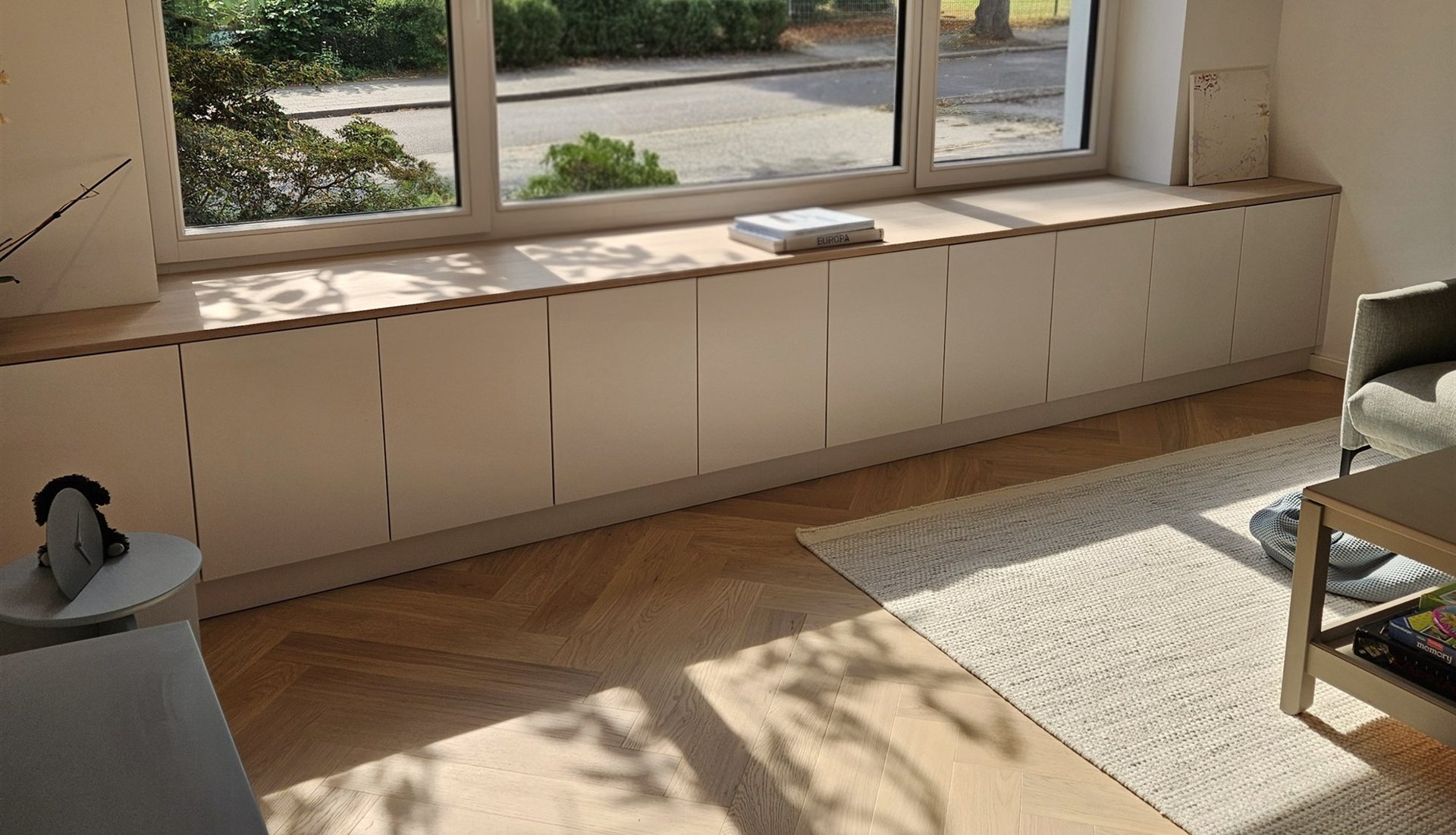 Maßgefertigte Lowboard-Anlage unter der Fensterfront mit Sonnenlicht auf Parkett, Essen