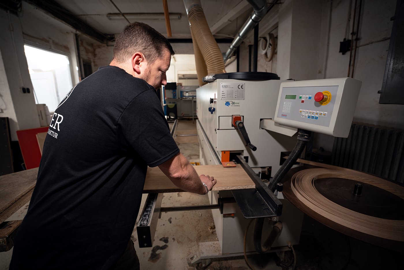 Mitarbeiter an der Kantenanleimmaschine in der Werkstatt der Holzmanufaktur Geier Essen